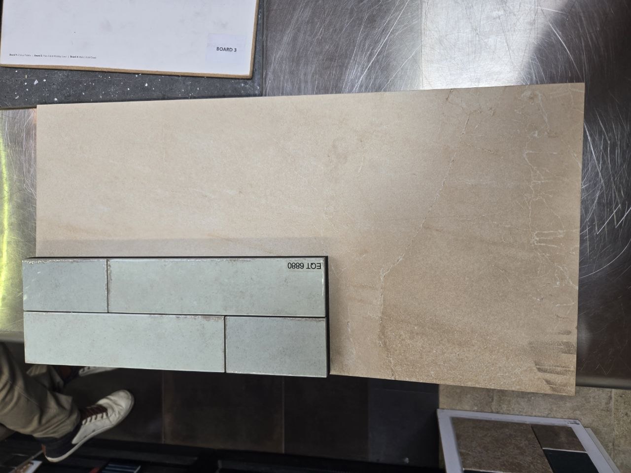 Detail view of green-gray tile arrangement with EOL 6880 text on beige slab