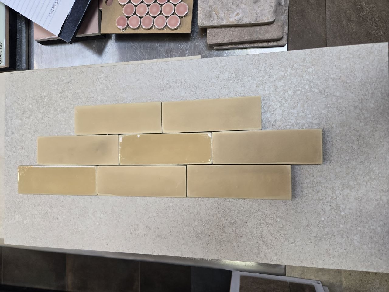 Yellow brownish-yellow glossy subway-style tile over speckled light stone slab