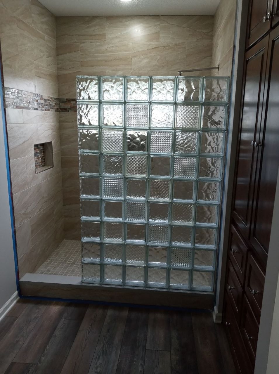 Doorless shower reference with glass block partition, neutral tile, and open entry